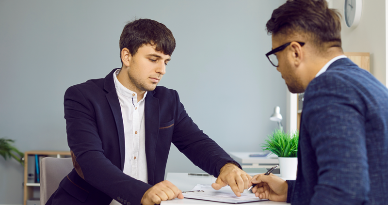 Zwei Männer besprechen einen Vertrag mit Unterschrift